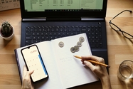 Persona en un escritorio con calculadora, portátil, lápiz y cuaderno 